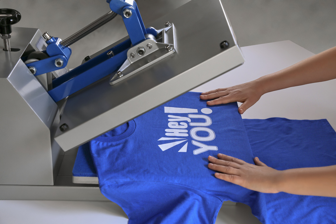 Printing Logo. Woman with T-Shirt Using Heat Press at White Tabl